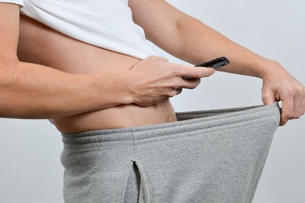 Isang tao ang nakatingin sa kanyang pantalon sa isang pinalawak na titi